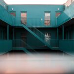 Modern interior view of a blue apartment complex featuring staircases and doors.